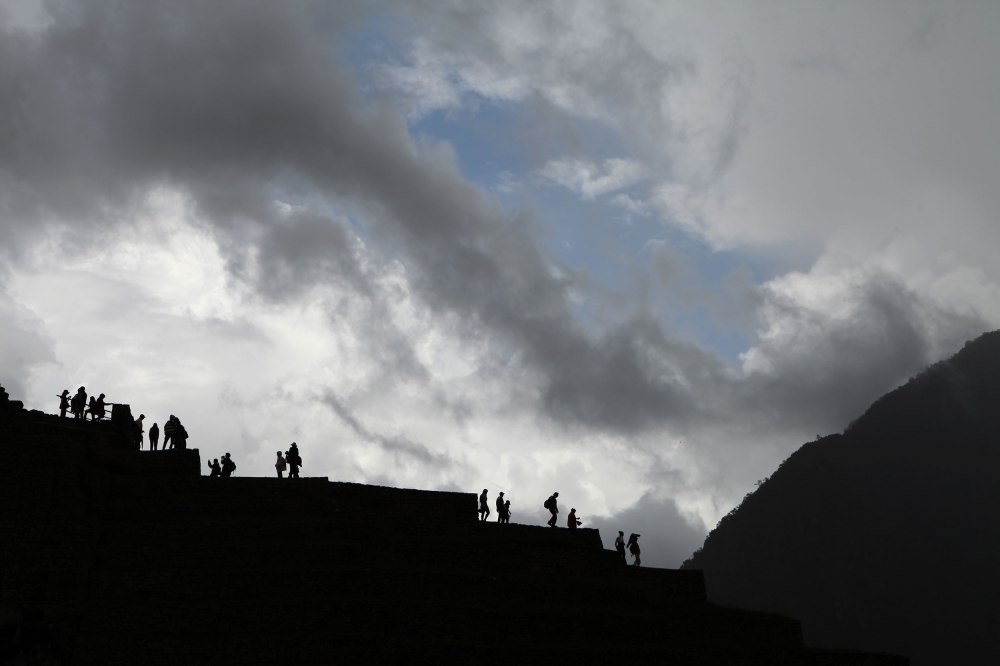 Tourists explore Machu Picchu as a rain storm rolls over the mountains. Photo: Alex Washburn